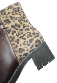 Ankle boot with dark brown leather front, leopard print suede back, and black chunky block heel.