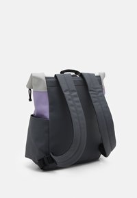 Sac à dos en tissu gris avec des accents violets, équipé de bretelles rembourrées, d'une poignée supérieure et de poches latérales. Texture lisse, design minimaliste.