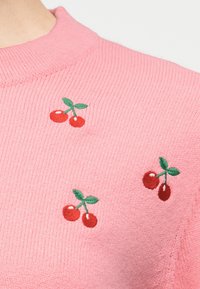 Tissu rose tricoté avec trois paires de cerises rouges brodées, accompagnées de feuilles vertes, dispersées dessus.