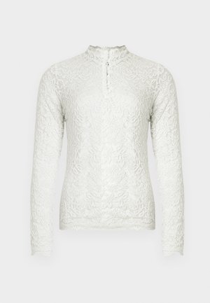 Bela dolga majica s dolgimi rokavi iz čipke, ki ima visok ovratnik z gumbom, cvetličnim vzorcem po celotni površini in teksturirano obdelavo.