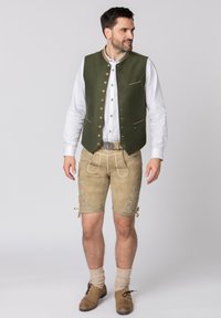 Traditionele Beierse outfit bestaande uit een groene, gestructureerde vest met gouden accenten, beige lederhosen met bloemgeborduurde details, en bruine schoenen.