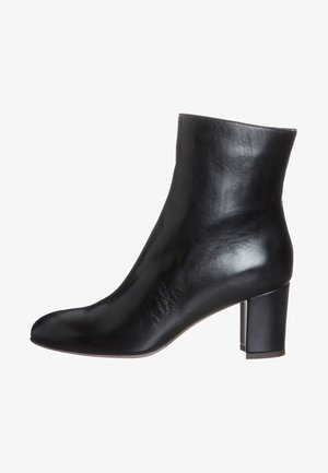 Bota de cuero negro hasta el tobillo con un diseño elegante, punta redondeada y tacón grueso. La superficie tiene una textura suave y un brillo sutil.