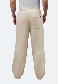 Beige Freizeithosen mit lockerer Passform, elastischem Bund und einer einzelnen Gesäßtasche. Hergestellt aus weichem Stoff mit glatter Textur.