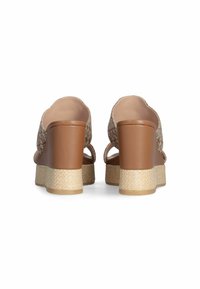 Sandales à plateforme marron avec un dessus texturé, présentant un design incurvé et découpé, ainsi qu'un accent en jute tressé sur le talon en coin.