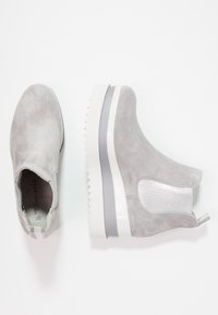 Harmaat mokkasiinit nilkkasaappaat, joissa on helposti päälle puettava muotoilu, joustavat sivupaneelit ja paksu valkoinen alustasaapas, jossa on harmaa korostusraita.