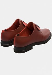 Braune Lederschuhe mit einem eleganten Design, runder Spitze, schwarzer Sohle und kontrastierender Innenseite. Die Schnürsenkel sind zentral positioniert.