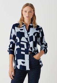 Kariertes Hemd in Marineblau und Hellblau mit geometrischen Mustern. Lange Ärmel, Knopfverschluss vorne und glatte Stoffoberfläche.