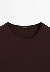 Dark burgundy T-shirt with a round neck. Made from textured fabric with ribbed detailing. Label reads "Massimo Dutti, Made in Portugal."