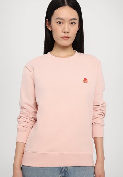 Lyserød crewneck sweatshirt lavet af blødt stof. Har ribbede manchetter og kant, med et lille broderet design på brystet.