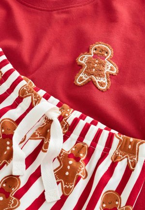 Red top with a gingerbread man embroidery; bottom features white and red striped fabric with gingerbread patterns and a drawstring waist.