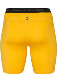 gula sportshorts med svart elastisk midja som har märket 'hummel' och en central detalj med chevron-design.