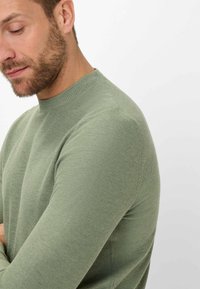 Grüner Strickpullover mit rundem Halsausschnitt und langen Ärmeln, aus einem strukturierten, leichten Stoff und mit einer taillierten Silhouette.