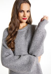 Maglione grigio a maglia con una vestibilità ampia, texture a coste e maniche larghe. Decorato con un collo rotondo e sottili variazioni di colore.