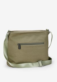 Bolso de lona verde oliva tipo bandolera con una correa de satén lisa y un bolsillo con cremallera en la parte frontal. Presenta herrajes en tono plateado y forma rectangular.