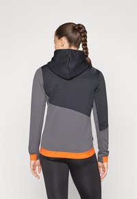 Hoodie s teksturiranim crno-sivim dizajnom, sa narančastim trakama na rubu i zapešćima. Glatka, prilagodjena silueta.