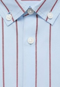 Cămașă albastru deschis cu guler, având dungi verticale de culoare maron. Butoane din plastic și cusături vizibile, cu o textură a stofei netedă.