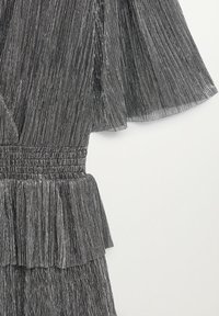 Robe rayée noire avec ourlet à volants, manches courtes et taille élastique pour un confort accru. Tissu texturé avec un design fluide.