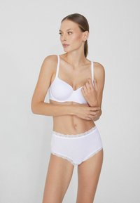 Biały stanik z gładkiego materiału i regulowanymi ramiączkami, w parze z wysokimi białymi majtkami z koronkowym wykończeniem na pasku.