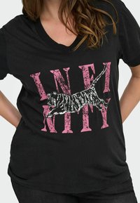 Zwarte v-hals t-shirt met een grafisch ontwerp met het woord "INFINITY" in versleten roze en een zwart-wit paillet tijgerillustratie.