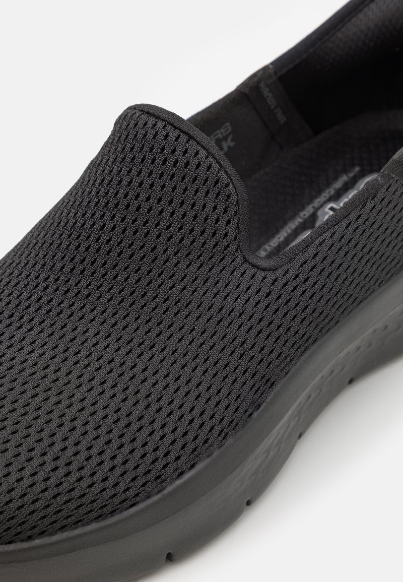 Scarpa slip-on nera realizzata in tessuto a maglia traspirante, con una superficie testurizzata e una suola in gomma spessa per il comfort.