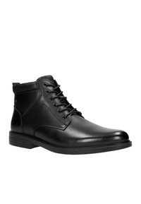 Czarne skórzane botki za kostkę o gładkiej fakturze, okrągłym nosku, sznurowanym przodzie i subtelnych detalach stegu. Solidna podeszwa z lekko podwyższonym obcasem.