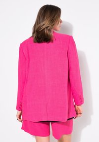 Fuchsia linneblazer med vadderade axlar, enkel sprund och treknappshandled, matchat med kortbyxor. Enkel design, lätt textur.