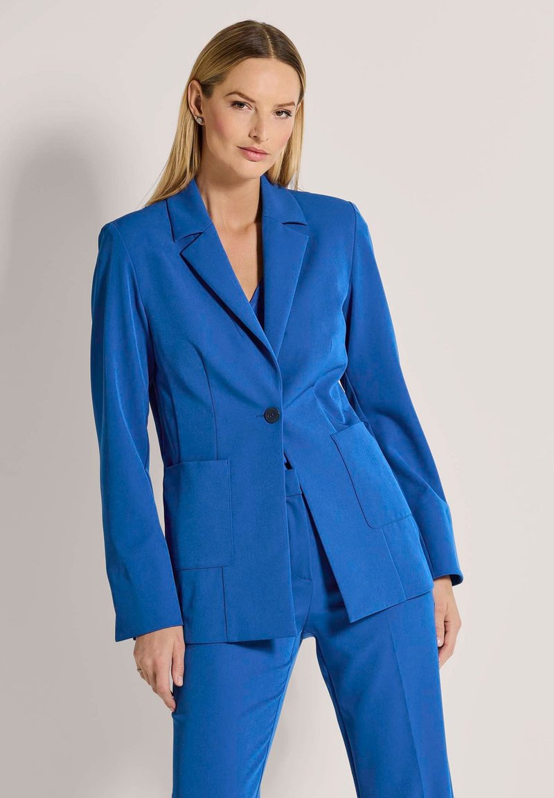 Blauwe blazer van soepel stof, met een enkele knoopsluiting, notch revers en twee voorkraagzakken. Getailleerde pasvorm.