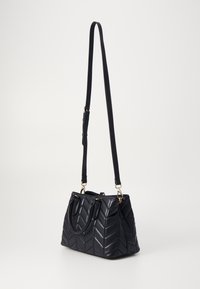 Tűzött fekete kézitáska, halszálka mintával, dupla fogantyúkkal, állítható vállpánttal és aranyszínű fém kiegészítőkkel.