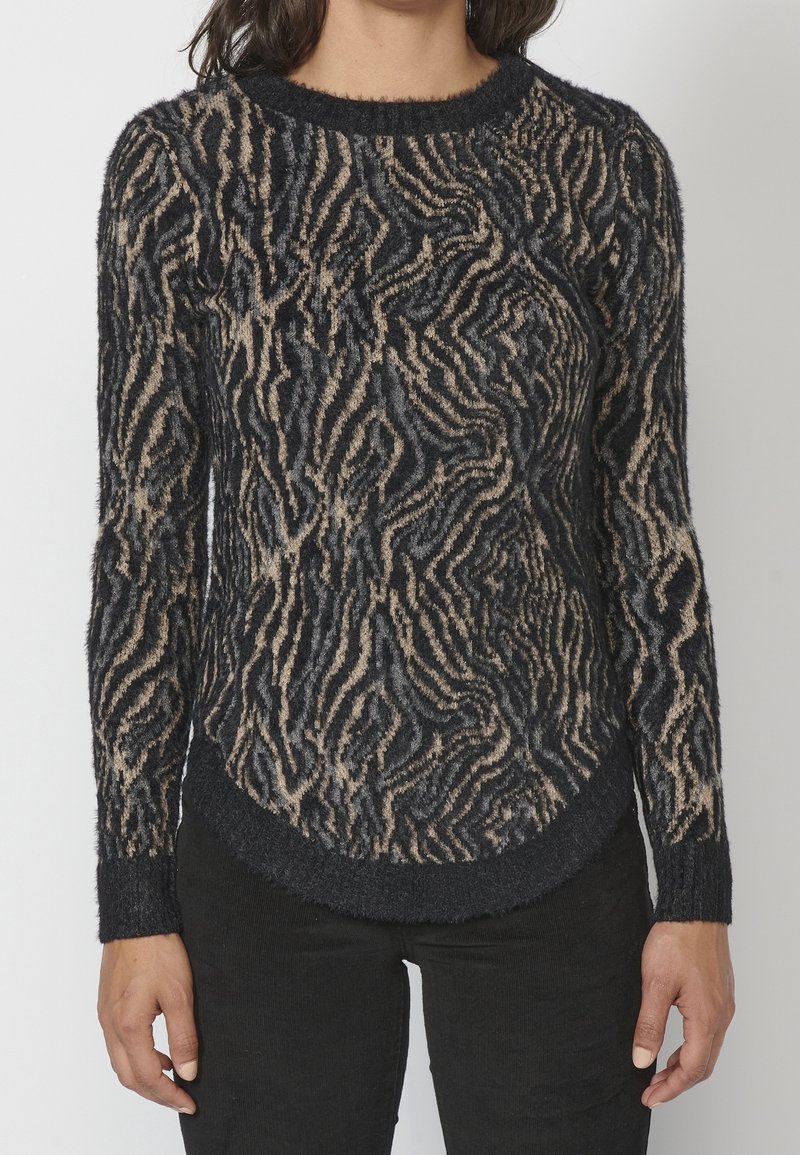 Suéter de patrón negro y beige con un acabado texturizado y suave, que presenta un cuello redondo y un dobladillo curvado. Mangas largas y puños ajustados.