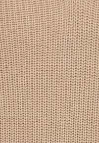 Tissu tricoté beige avec un motif fin et texturé. Fabriqué en matériau doux, présentant des points espacés uniformément.