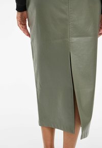 Khaki faux nahkast midi seelik külgsuuga lõhe ja sileda tekstuuriga. Omab puhta alläärega ja minimalistlikku disaini.