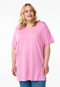 Pink, short-sleeve V-neck T-shirt in a soft, lightweight fabric with a relaxed fit and side slits, paired with blue denim.