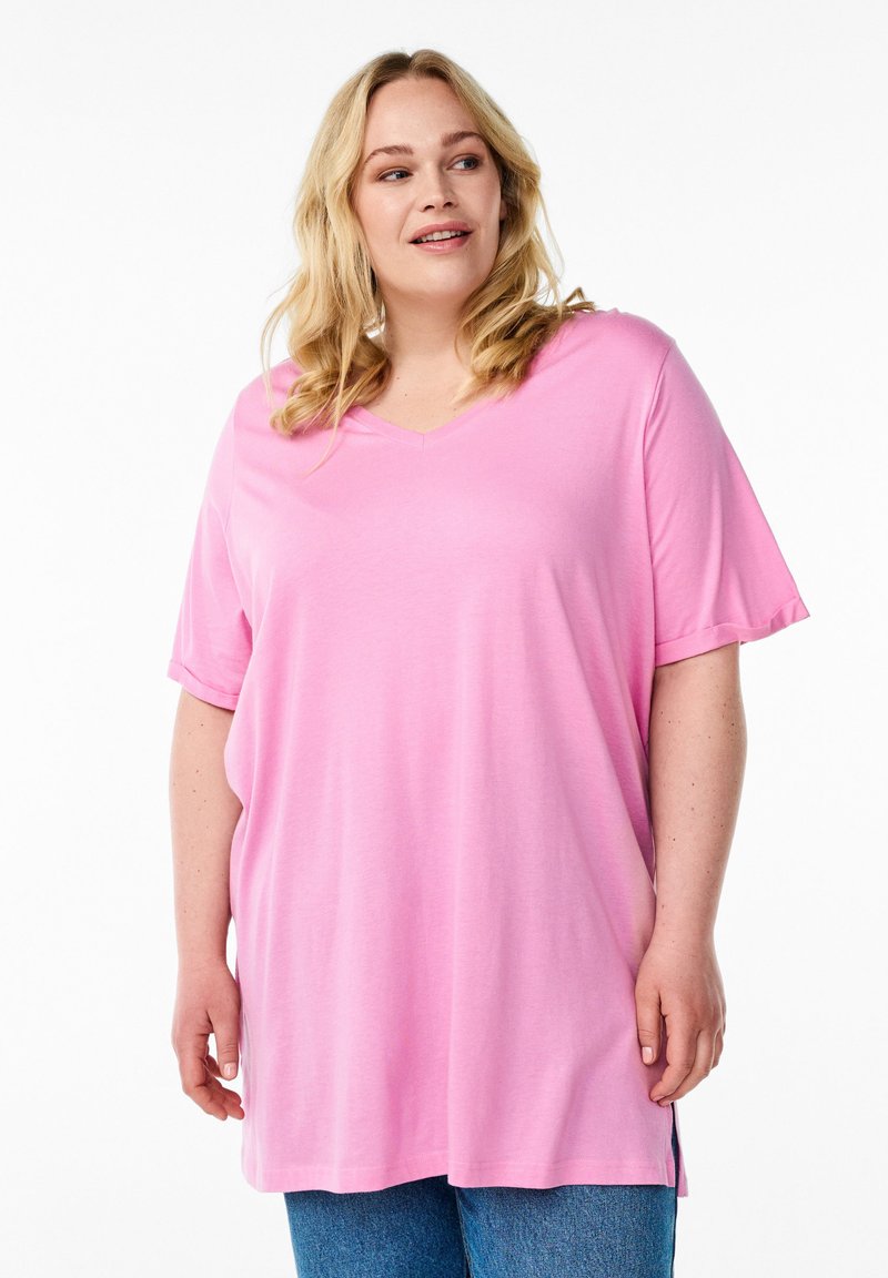 Pink, short-sleeve V-neck T-shirt in a soft, lightweight fabric with a relaxed fit and side slits, paired with blue denim.