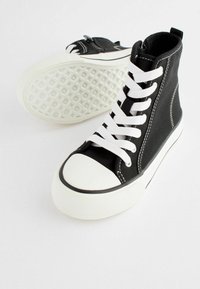 Schwarze Canvas-Hochtop-Sneaker mit weißen Schnürsenkeln, Gummikappe, strukturierten weißen Sohlen, Nähdetails und einem seitlichen Reißverschluss.