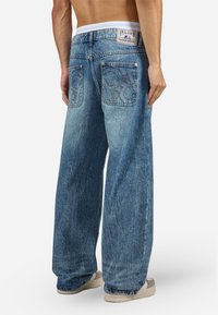 Light blue denim wide-leg jeans with a high waist, featuring two back pockets with embroidered designs and a branded waistband.