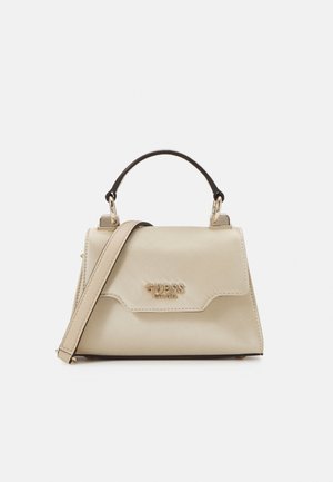 Béžová kabelka Guess s horní rukojetí, odnímatelným páskem na rameno a zlatým logem "GUESS EST 1981" na přední chlopni.