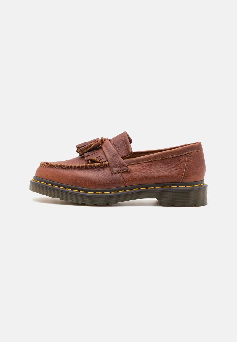 Mocassin en cuir marron avec des franges, couture jaune et semelle en caoutchouc épaisse, présenté de côté sur un fond blanc.