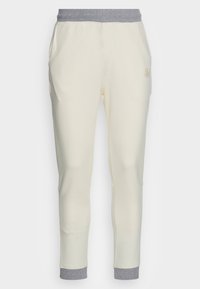 Krämfärgade sweatpants med ett grått elastiskt midjeband, sidofickor, smalnande ben och broderad logodetalj på framsidan.