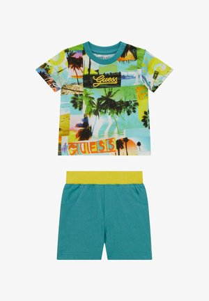 T-shirt colorato a maniche corte con stampa tropicale e logo 'Guess'; abbinato a pantaloni corti teal con una cintura elastica gialla.
