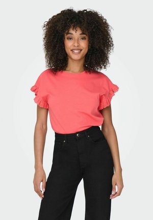 Koronkowy t-shirt z krótkim rękawem w kolorze koralowym, ozdobiony falbankami, zestawiony z czarnymi spodniami o wysokim stanie. Gładka bawełniana tekstura, luźny krój.