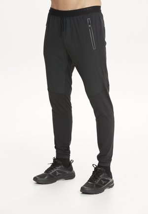 Black athletic pants made of stretchy, lightweight material. Features a drawstring waist and a zippered pocket on the front.