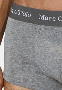 Graue Baumwoll-Boxershorts mit weicher Textur, ausgestattet mit einem dunkelgrauen Bund, der mit "Marc O'Polo" in weißer Schrift bedruckt ist.
