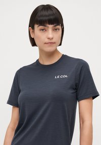 Dark gray short-sleeve t-shirt made of lightweight, smooth fabric featuring a white "LE COL" logo on the upper left chest area.
