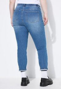 Obepnuté modré džíny z denimu s hladkou strukturou, zužující se nohavice, ohrnutý lem a zadní kapsy. Elastický pas pro pohodlí.