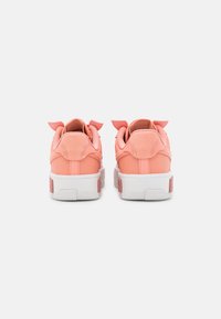 Pink synthetic sneakers with white rubber soles, featuring soft suede detailing at the heel and playful fabric accents at the back.