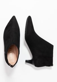 Stivali alla caviglia in suede nero con punta affusolata, tacco a blocco e design con lato aperto. Presentano una fodera interna liscia e una chiusura con zip.