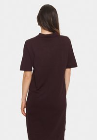 Robe à manches courtes, de couleur bordeaux foncé, fabriquée en tissu doux. Présente un design simple avec un col et une coupe décontractée.