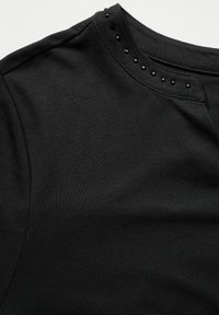 T-shirt nera con scollo rotondo e borchie nere decorative lungo la cucitura della spalla. Tessuto morbido e liscio con una forma aderente.