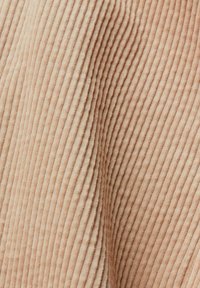 Close-up of beige corduroy fabric showing soft, vertical ridges and textured folds.