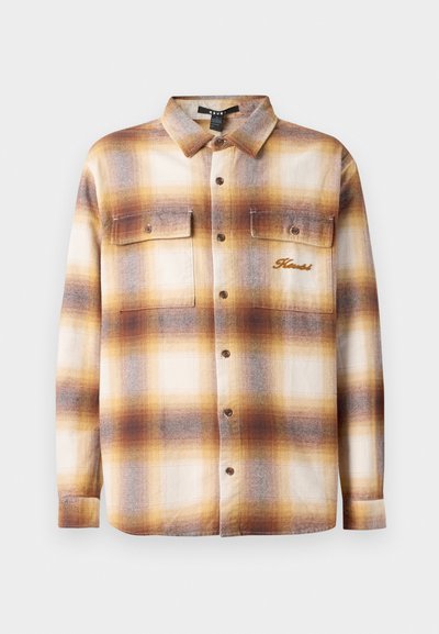 Brun og kremfarget rutete skjorte med knappefront, to brystlommer og brodert merkevarelogo på venstre side. Laget av et strukturert stoff.